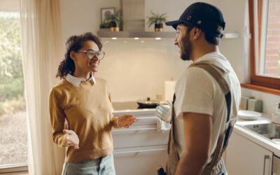 Repair man speaking to a woman in a house.
