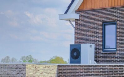 An air-source heat pump unit is installed outdoors at a modern brick home for efficient heating and cooling.