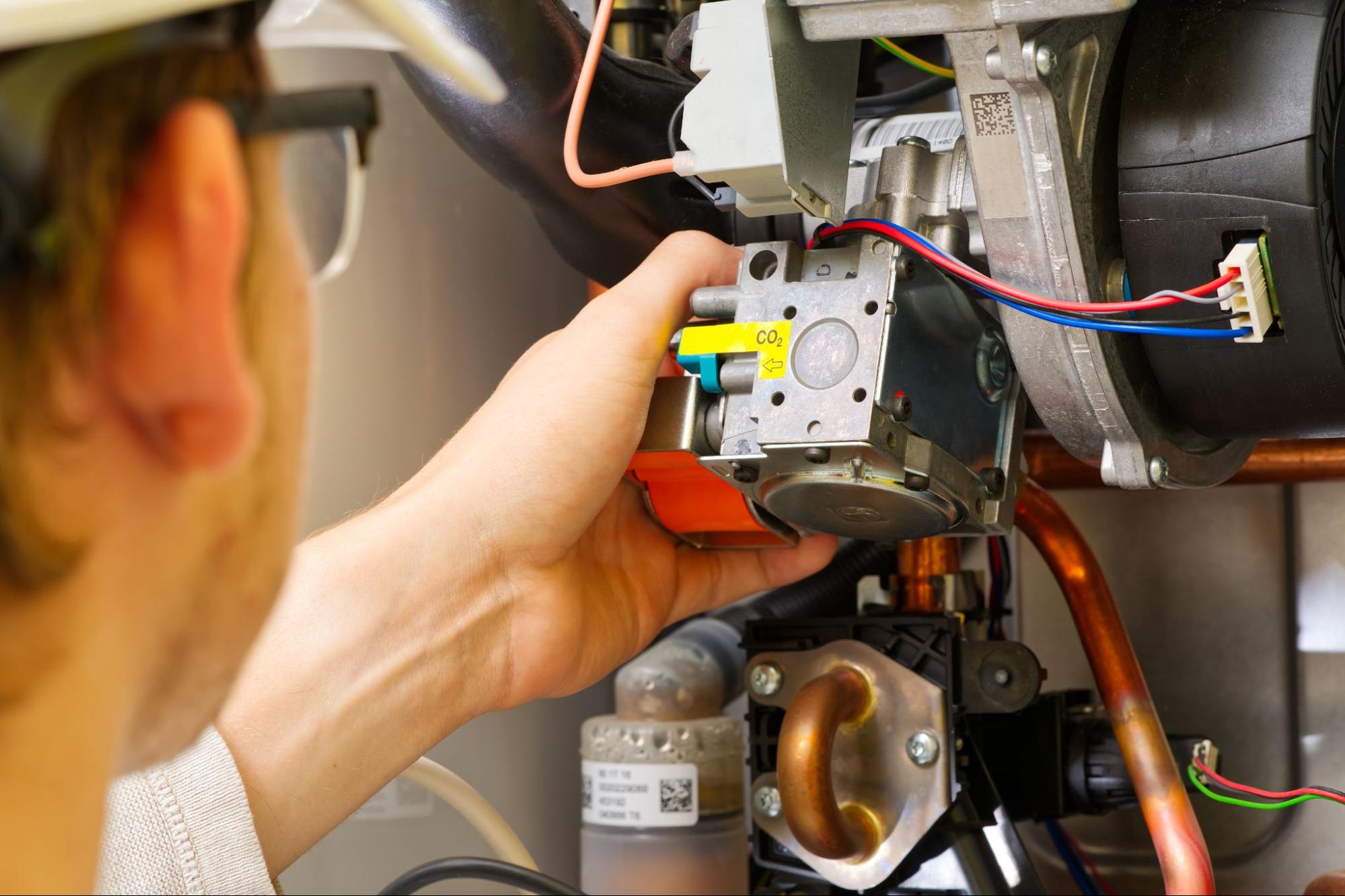A technician performing repair heating service on a residential gas boiler.