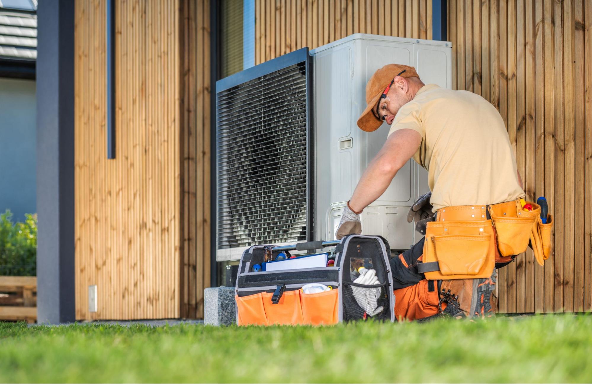 A technician is installing a new HVAC system outside a house.