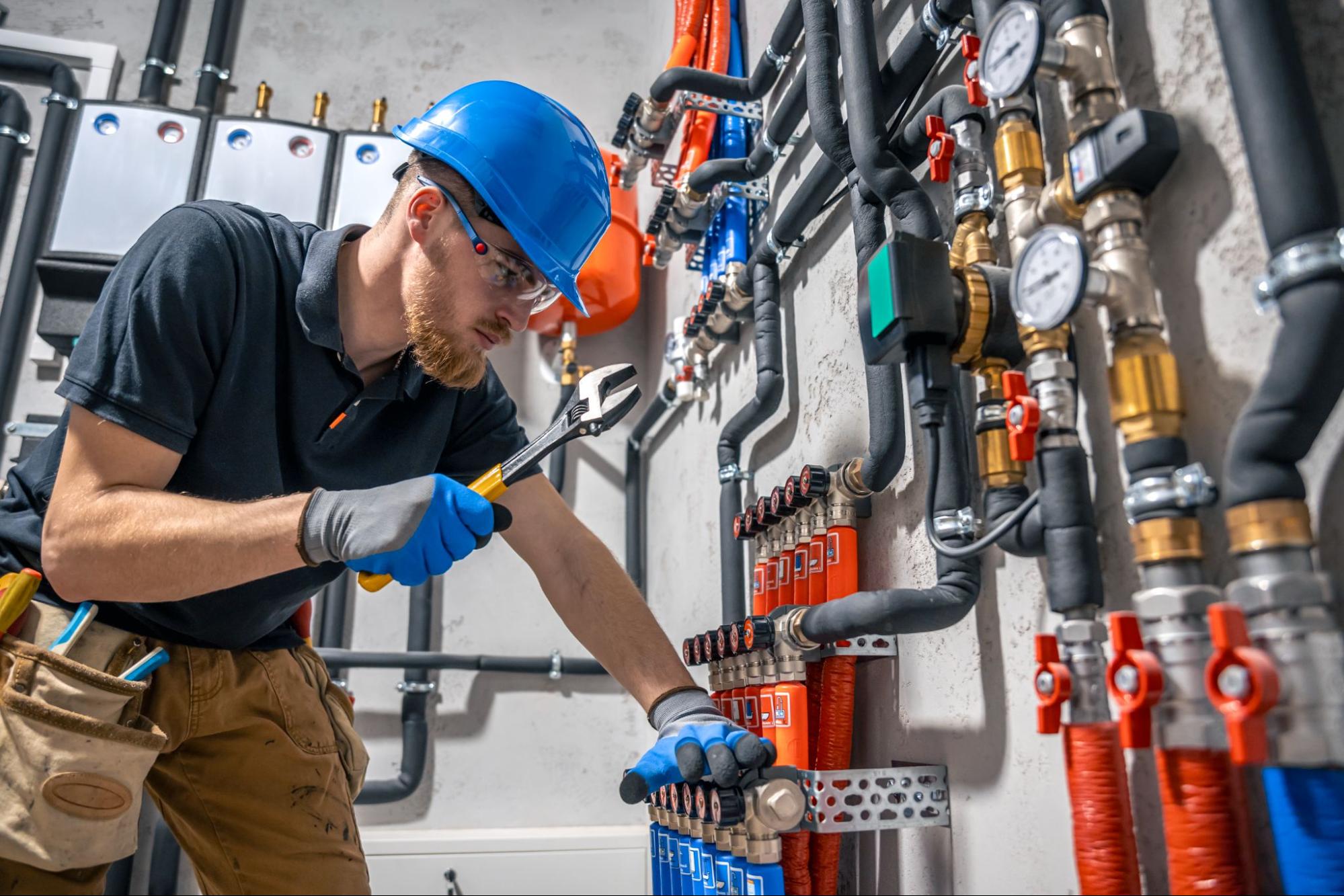 An HVAC technician inspects a heating system in a boiler room.