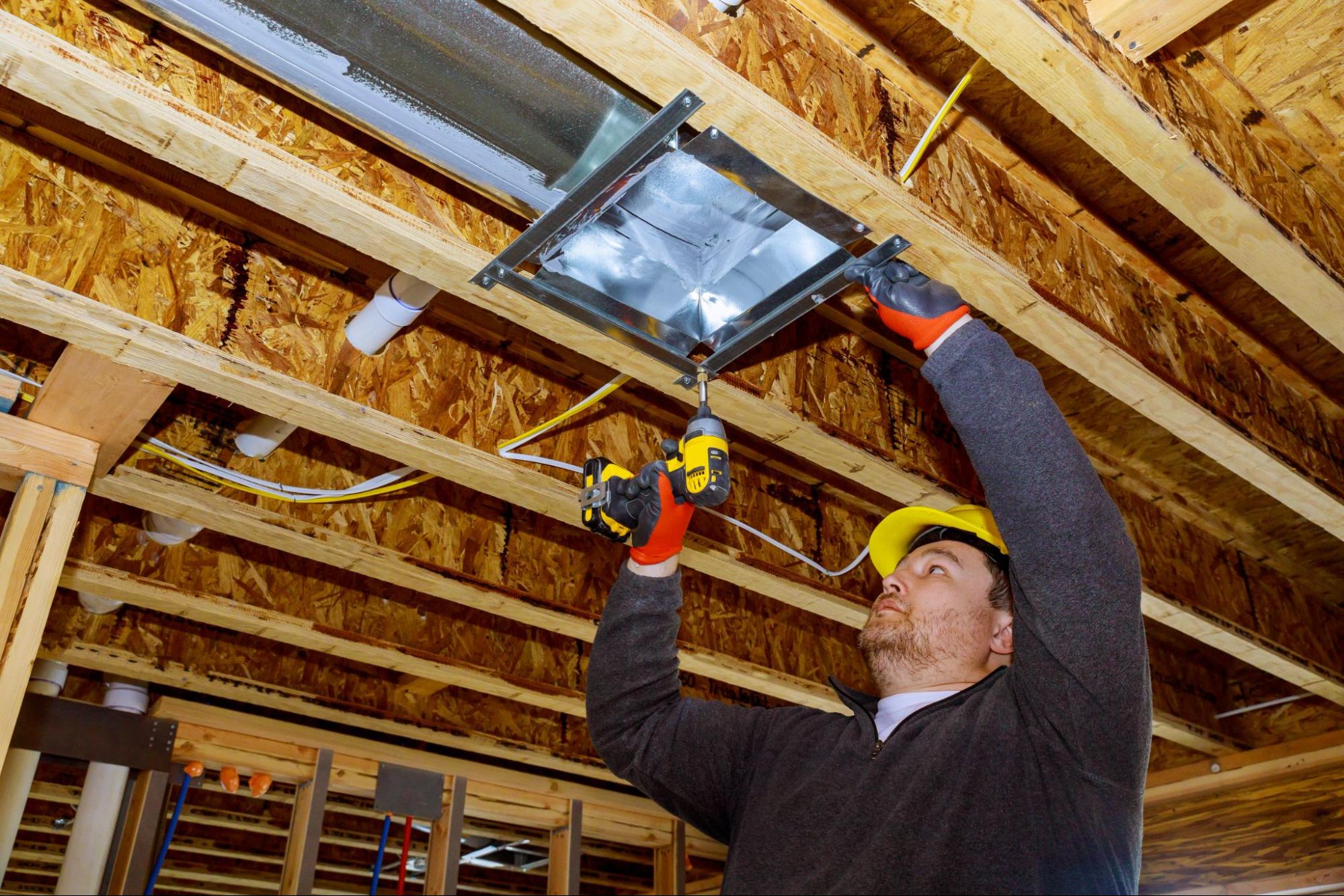 Technician completing a heating installation on a ceiling-mounted air system.