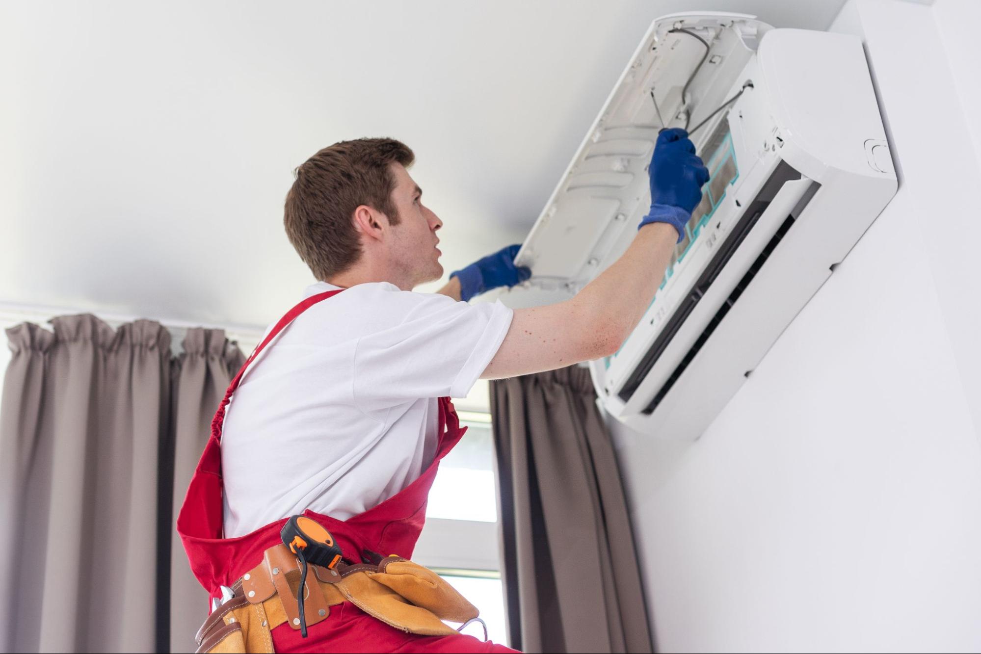 A technician performing air conditioning repair service on a modern indoor unit.