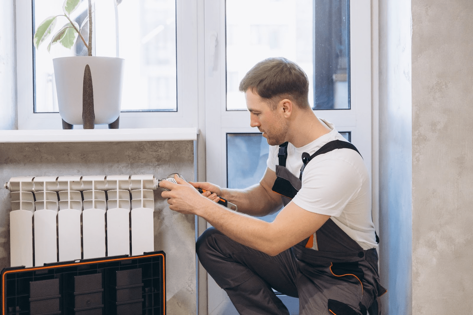 A technician repairs a heating radiator in a residential apartment.